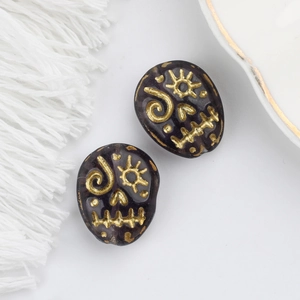 Detail of Czech glass beads with gold-painted skull designs for DIY jewelry crafts