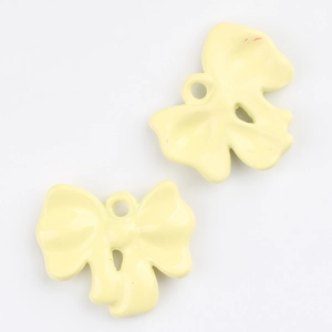 Macro shot of light yellow alloy bow pendant with round hanging hole for DIY jewelry