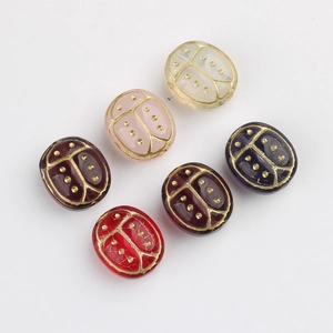 Macro shot of six hand-painted Czech glass beetle beads with gold-painted wing patterns