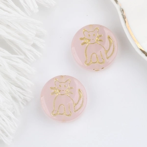 Detail of pink translucent glass cat beads with gold engraved edges for DIY jewelry
