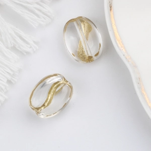 Macro detail of transparent oval glass beads with gold sand texture for DIY jewelry making