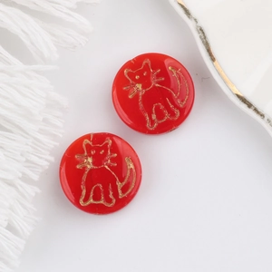 Detailed macro of red Czech glass beads featuring hand-painted gold cat patterns for DIY