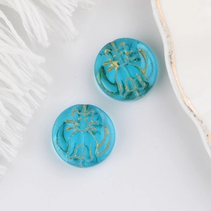 Detail of round blue glass cat beads with gold engraved cat pattern for DIY jewelry