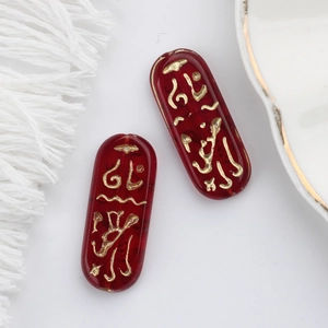 Macro view of dark red Czech glass beads with gold Egyptian runes for DIY jewelry