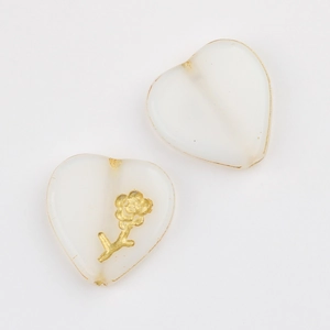 Detailed macro of vintage white heart glass beads with gold accents for DIY jewelry