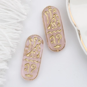 Detail of pink Czech glass bead with gold Egyptian runes for DIY bracelet crafting