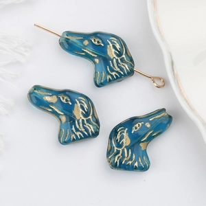 Dettaglio di perla di vetro blu a forma di cane con accenti dorati per gioielli e bracciali