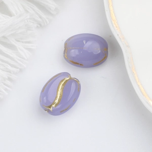 Macro detail of purple Czech glass oval beads with gold-painted vintage textures for DIY