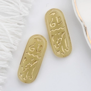 Macro shot of oval Czech glass charms with gold Egyptian rune engraving for jewelry making