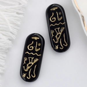 Macro view of black Czech glass beads with engraved gold Egyptian hieroglyph symbols