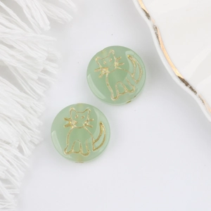 Macro shot of green Czech glass beads with gold cat engraving for jewelry making