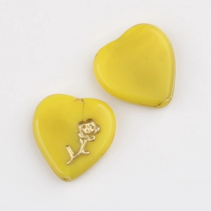 Macro shot of yellow heart glass beads with gold flower pattern for DIY jewelry