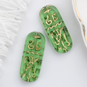 Macro shot of green Czech glass beads with gold Egyptian runes and central drilling