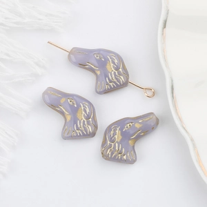 Vista macro di perle di cane in vetro ceco viola con accenti dorati per gioielli fai-da-te