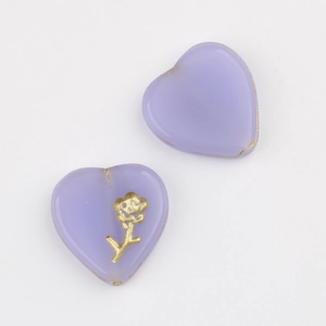 Macro shot of heart-shaped lavender glass beads with gold flower pattern for DIY jewelry