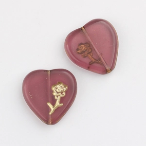 Macro view of heart-shaped Czech glass beads with gold floral patterns for DIY jewelry