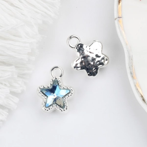 Macro detail of star-shaped charm with blue crystal inlay and vintage hammer texture