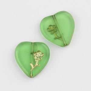 Macro shot of green heart-shaped glass beads with gold flower pattern for DIY jewelry