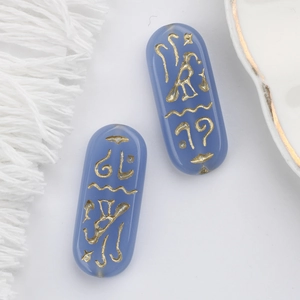 Macro detail of blue glass beads with gold Egyptian runes for DIY jewelry making