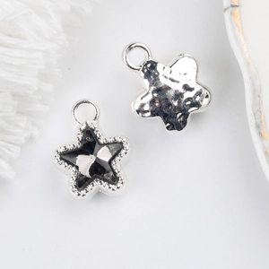 Macro shot of 11mm star charms featuring faceted gray zircon and hammered silver texture
