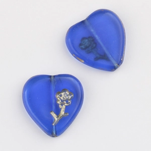 Macro detail of heart-shaped blue glass beads with gold floral engraving for DIY jewelry