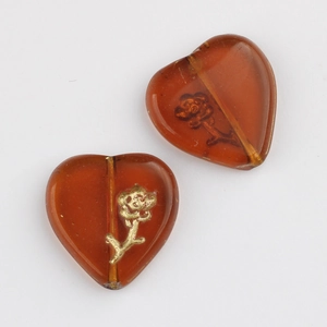 Detailed view of amber glass heart beads with golden rose patterns for DIY jewelry