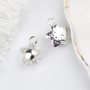 Macro shot of silver star pendants with sparkling zircon and hammered metal texture