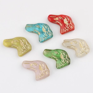 Dettaglio di perline in vetro colorato a forma di cane con contorno dorato per DIY