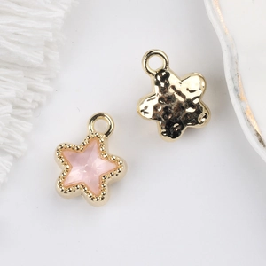 Detail view of star-shaped charms with pink crystal inlay and hammered gold texture