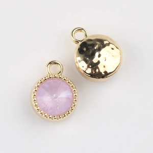 Detail of round light purple gemstone pendant with golden beaded edge and hammered back