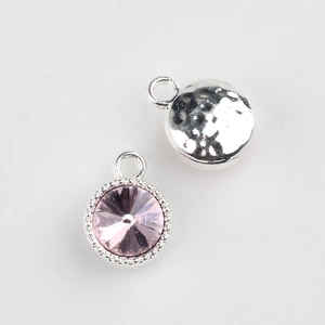 Macro detail of pink rhinestone pendant with beaded silver bezel and hammered back texture
