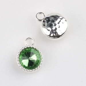 Detail showing emerald green crystal pendant with silver textured edge and metal back
