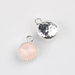 Detailed view of silver round bezel pendant with pink crystal and hammered metal texture