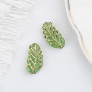 Detailed view of green Czech glass leaf beads with gold veined texture and scalloped edges