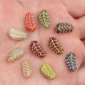 Czech glass leaf beads with gold veined accents in assorted colors shown on hand