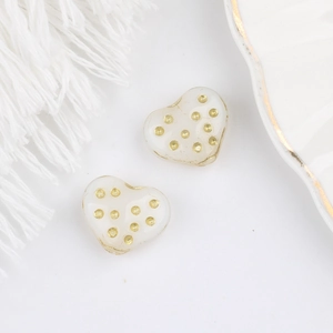Dettaglio macro di perle di vetro a forma di cuore crema con pois dorati per gioielli
