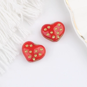 Dettaglio di perline a cuore rosse con pois dorati per la creazione di gioielli
