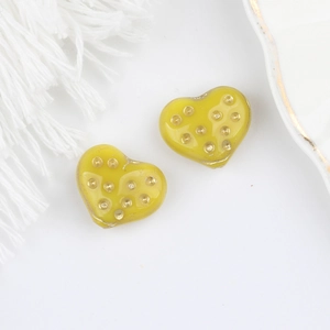Dettaglio di perline di vetro a cuore giallo con puntini d'oro per gioielli fai da te