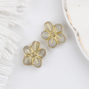 Macro detail of translucent grey glass flower beads with vintage gold leaf gilding patterns