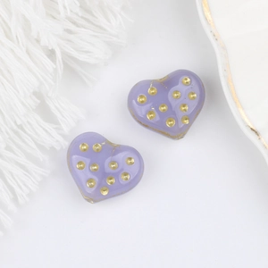 Dettaglio di perline a cuore in vetro viola con pois dorati per creazione di gioielli