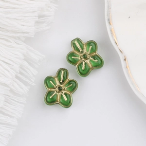 Detailed view of two green glass flower beads with vintage gold gilded edges for DIY crafts