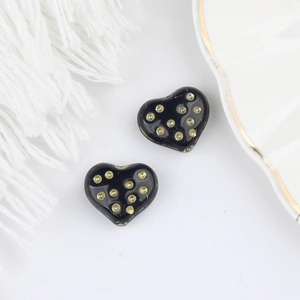 Dettaglio di perline di vetro nero a forma di cuore con pois dorati per gioielli fai da te