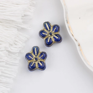 Macro shot of blue five-petal glass beads with gold accents for DIY jewelry making