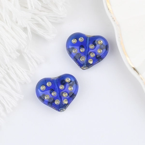 Dettaglio macro di perle a cuore in vetro blu con pois dorati per gioielleria