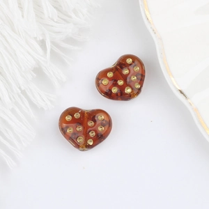 Dettaglio macro di perle di vetro a cuore ambra con pois dorati per gioielli DIY