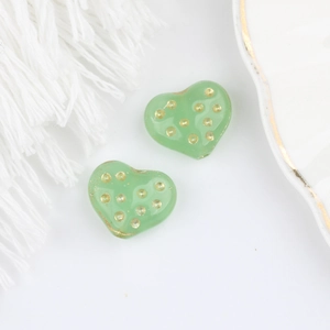 Dettaglio di perline di vetro ceco a cuore verde con pois dorati per gioielli fai-da-te