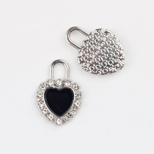 Macro shot of black heart lock charm with clear crystal inlay and silver metal backing