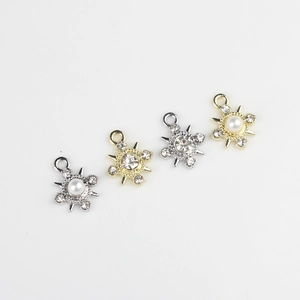 Primer plano de dijes de copos de nieve con perlas y pedrería para joyería artesanal