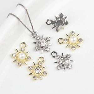 Detalle de dijes de estrella con perlas y pedrería en acabados dorado y plateado