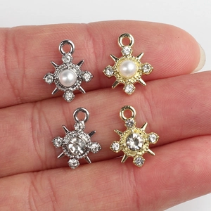 Colgantes estrella de oro y plata con perlas y strass mostrados a escala en los dedos